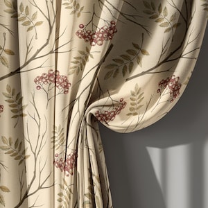 May include: Beige curtain with a repeating pattern of branches, leaves, and clusters of red berries. The fabric is draped, showing the texture and design. The curtain is against a gray wall.