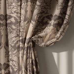 May include: Close-up of a beige and brown patterned curtain. The fabric features a repeating design of stylized leaves and scrolls. The curtain is draped, revealing the texture and pattern of the fabric. The color palette is neutral, with shades of beige and brown.