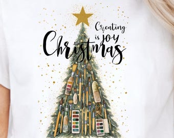 Camiseta navideña "Crear es alegría" con diseño artístico de árbol. Ideal para artesanos, pintores y personas con espíritu creativo.