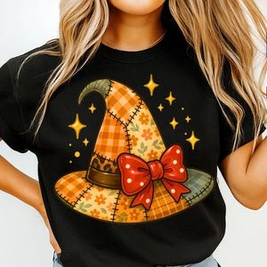 Könnte beinhalten: Schwarzes T-Shirt mit einem bunten Hexenhut-Design. Der Hut hat ein Patchworkmuster mit orangefarbenen, gelben und grünen Abschnitten, eine rote Schleife und goldene Sternakzente. Das Design ist skurril und festlich.
