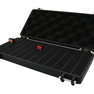 May include: Black hard-shell carrying case, open to reveal a grid-like interior and a foam-padded top. Two small, rectangular items with red and white labels are visible inside the case. The case has metal hinges and latches.