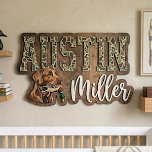 May include: A custom wooden wall sign featuring the name AUSTIN in block letters with a green camouflage pattern and the name Miller in white cursive script. A brown Labrador retriever holding a mallard duck in its mouth is depicted below.
