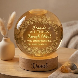 May include: A spherical glass lamp with the text "I can do ALL THINGS through Christ who strengthens me. Philippians 4:13" and a floral design. The lamp is illuminated and sits on a wooden base engraved with the name "Daniel".