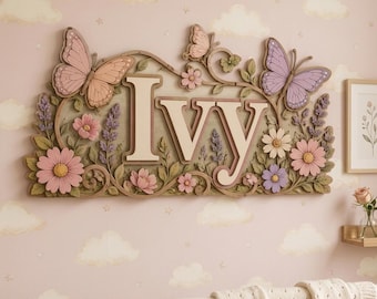 Puede incluir: Un letrero de madera para pared con el nombre Ivy en letras mayúsculas grandes de color crema. El letrero está decorado con mariposas talladas en tonos pastel, hojas verdes y varias flores rosas, moradas y blancas en un marco floral.