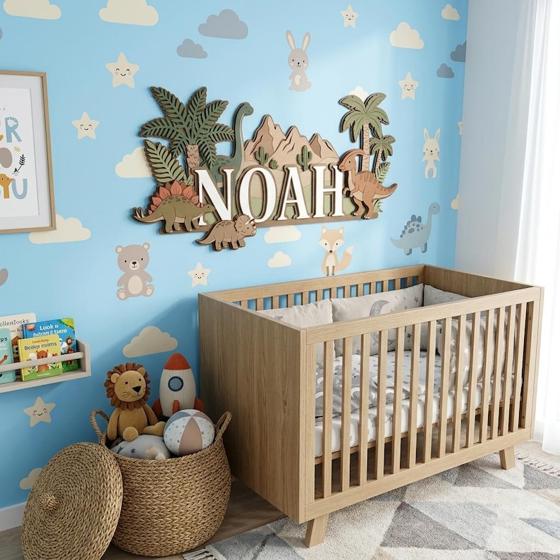 Pu&ograve; includere: Una scena di cameretta con una culla in legno, un cesto di vimini pieno di giocattoli e una parete blu decorata con nuvole, stelle e animali. Un cartello in legno recita "NOAH" con dettagli di dinosauri e palme.