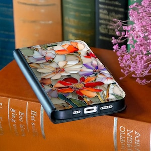 May include: A black phone case with a colorful floral design. The case features a stained-glass style pattern of red, orange, purple, and white flowers. The case is open, revealing the phone's screen and ports.