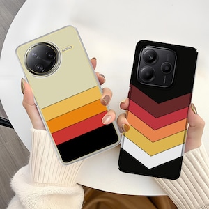 May include: Two phone cases with retro-style designs. One case has horizontal stripes in beige, yellow, orange, red, and black. The other case features a chevron pattern in burgundy, red, orange, yellow, and white on a black background.