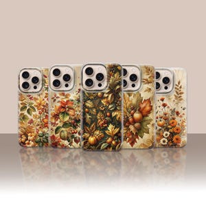 May include: Five clear smartphone cases arranged in a row, each featuring a distinct autumn-themed design. The patterns include vibrant fall foliage, orange pumpkins, acorns, berries, and various seasonal flowers in shades of gold, brown, and orange.