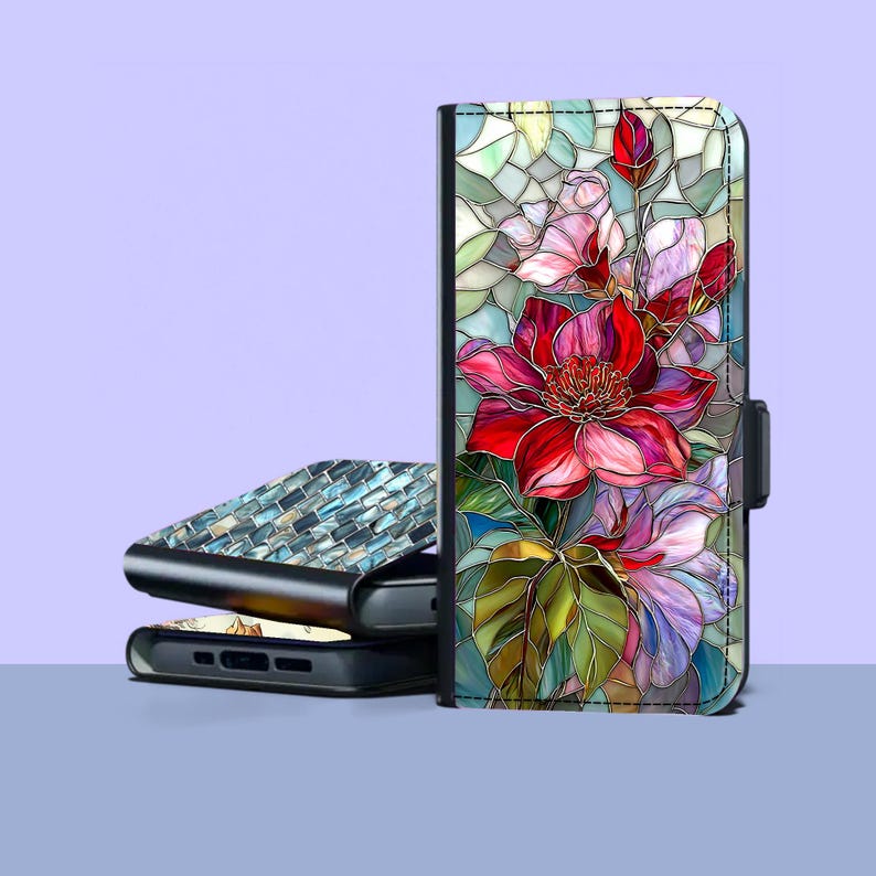 Peut inclure: Un &eacute;tui de t&eacute;l&eacute;phone noir avec un motif floral en vitrail aux fleurs rouges, roses et violettes. L'&eacute;tui est dot&eacute; d'une fermeture magn&eacute;tique. Un autre &eacute;tui de t&eacute;l&eacute;phone avec un motif de mosa&iuml;que est empil&eacute; en dessous.