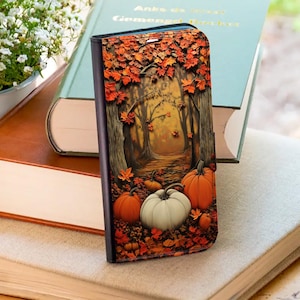 May include: A rectangular phone case featuring a printed design of an autumn forest scene. The image displays a path through trees with orange and red fallen leaves, accompanied by several orange and white pumpkins resting on the ground.
