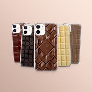 Può includere: Una collezione di cinque custodie per telefono con design a forma di barretta di cioccolato. Le custodie presentano varie tonalità di marrone e bianco, che imitano cioccolato al latte, fondente e bianco.
