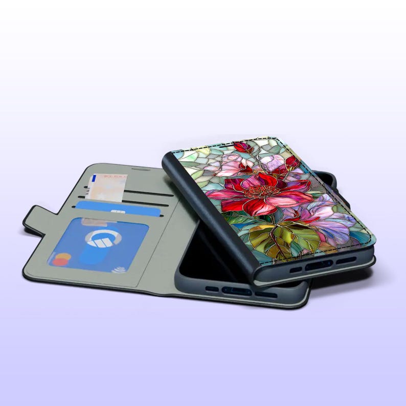 Peut inclure: Un &eacute;tui de t&eacute;l&eacute;phone avec un motif floral en vitrail. L'&eacute;tui est ouvert, r&eacute;v&eacute;lant un int&eacute;rieur gris avec des fentes pour cartes et une carte de cr&eacute;dit bleue. L'&eacute;tui de t&eacute;l&eacute;phone pr&eacute;sente un motif de fleurs rouge et rose vif.