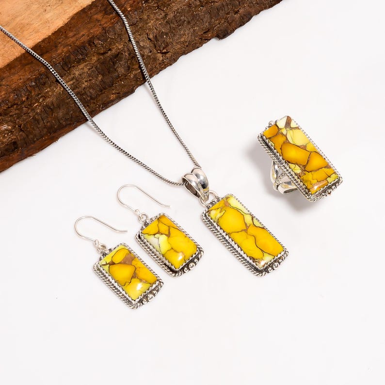 May include: A jewellery set comprising a necklace, earrings, and a ring. Each item features a rectangular yellow and white stone set in silver-coloured metal. The earrings are hook-style, and the ring has a wide band.