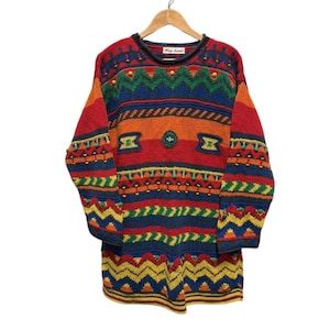 May include: A multi-coloured, long-sleeved sweater with a round neckline. The sweater has a vibrant pattern of horizontal stripes in red, orange, blue, green, and yellow, with gold-coloured accents. The label reads "Fay Lane".