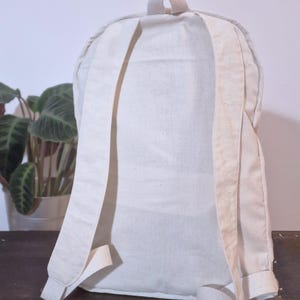 Puede incluir: Una mochila color crema con correas ajustables y un asa superior. La bolsa est&aacute; hecha de una tela resistente y texturizada y tiene un dise&ntilde;o simple y minimalista. Las correas y el asa son de un tono crema ligeramente m&aacute;s claro.