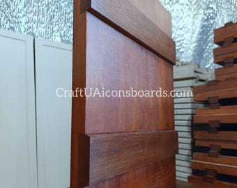May include: A wooden structure with a reddish-brown finish, featuring horizontal dark brown accents. The design includes a base and a vertical panel with the text "CraftUAIconsboards.com". The wood grain is visible, and the construction appears sturdy.