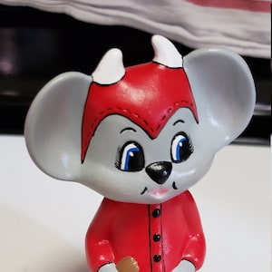 May include: A ceramic figurine of a gray mouse wearing a red devil costume and holding a brown bag that says "Treats".