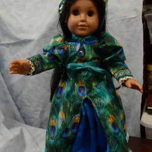 May include: A doll wearing a blue and green peacock-patterned dress with a blue satin skirt and a green beaded crown.
