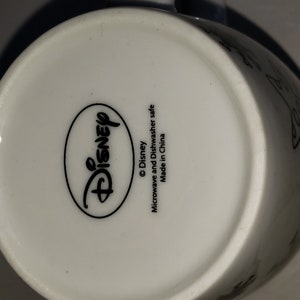 May include: White ceramic mug with a black Disney logo and the text "Microwave and Dishwasher safe. Made in China."