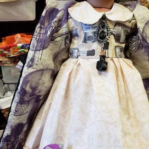May include: A doll wearing a cream-colored dress with a white collar and a patterned bodice. The doll has dark hair and is accessorized with a black pendant. A purple toy dragon sits on a jar with a skull label.