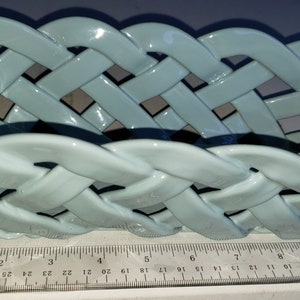May include: A light blue ceramic woven basket, approximately 10 inches long, with a glossy finish.