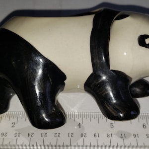 May include: A ceramic panda planter with black and white markings. The planter is approximately 6 inches long.