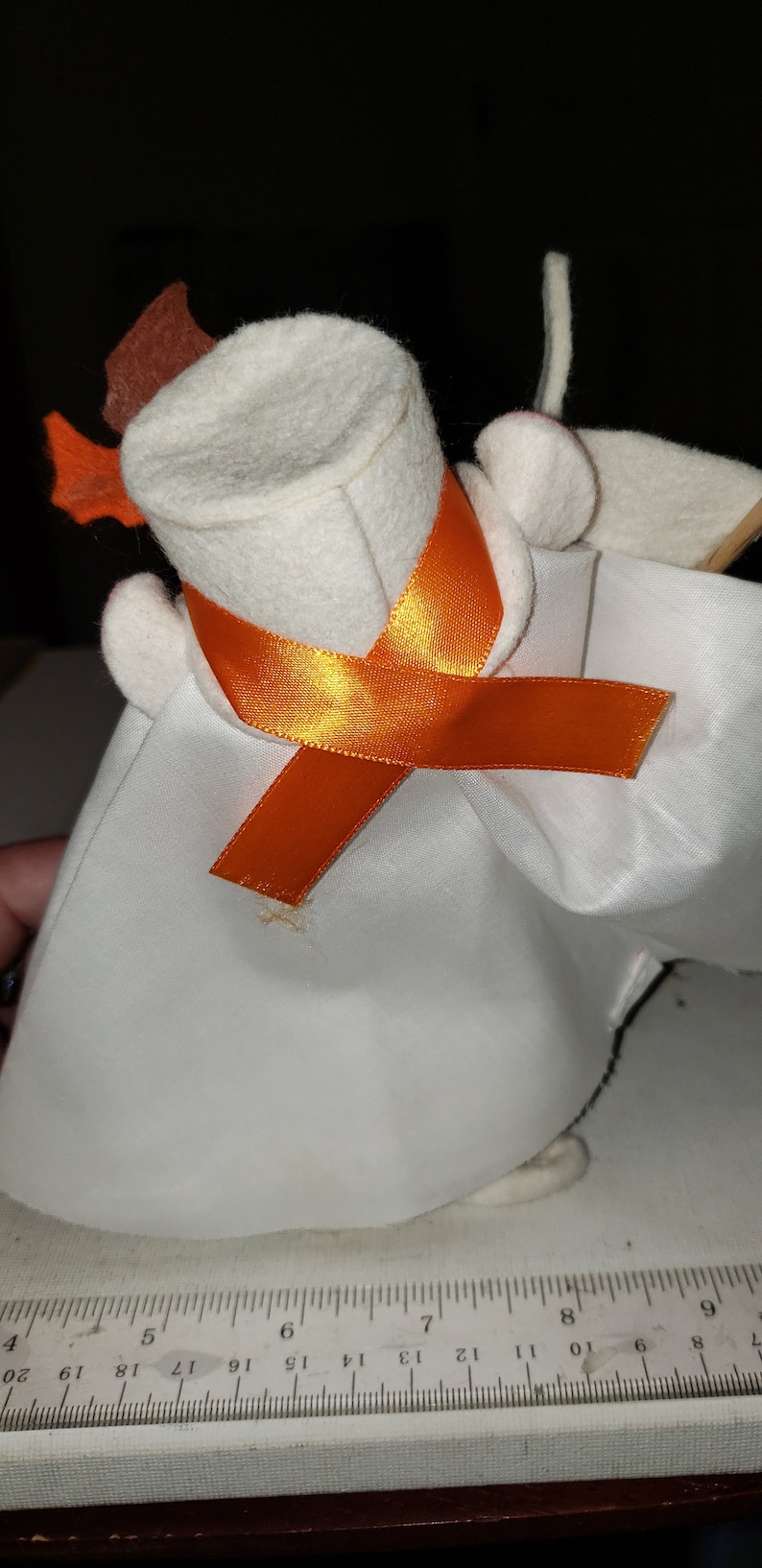 Puede incluir: Un fantasma de fieltro blanco con un sombrero de fieltro marr&oacute;n y una cinta naranja. El fantasma lleva una t&uacute;nica de fieltro blanco.