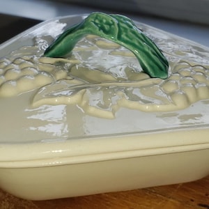 Triangular ceramic lidded dish; white with green handle and grapes; excellent condition; one very tiny chip covered by lid