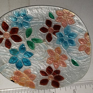 May include: A white oval dish with a raised floral design. The flowers are painted in shades of red, blue, pink, and green.