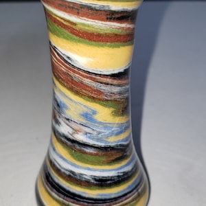 May include: A small, colorful ceramic vase with a swirling pattern of yellow, green, blue, red, and black. The vase has a narrow neck and a wide base.