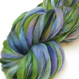 May include: A skein of hand-dyed yarn in shades of green, blue, and purple. The yarn is arranged in a loose, swirling pattern.