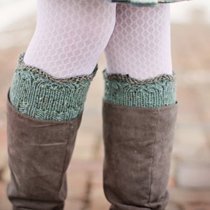 Puede incluir: Un par de botas de cuero marrón con polainas de punto verde y marrón. Las polainas tienen un borde festoneado.