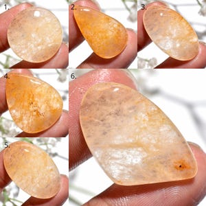 Può includere: Una collezione di sei pietre preziose levigate e traslucide color pesca con inclusioni naturali e forme varie, tra cui rotonde, ovali e a goccia, ognuna con una superficie liscia e lucida e calde tonalità arancione chiaro.