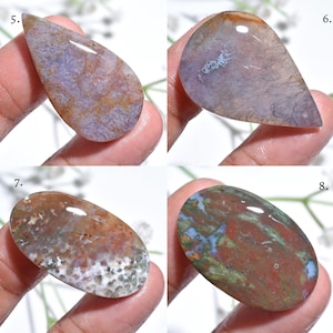May include: Four polished gemstones in various shapes. The stones display a range of colors, including purple, brown, red, green, and blue. Each stone has unique patterns and textures, with some featuring dendritic inclusions.