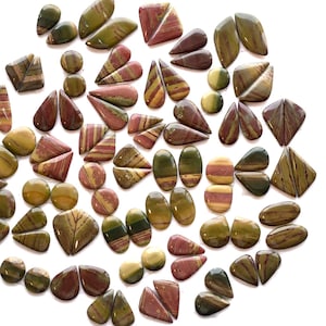 以下が含まれることがあります： 楕円形、涙形、幾何学的な形など、さまざまな形の研磨された宝石のコレクション。石は、緑、赤、黄色などの色の混合物を示し、縞模様と模様のあるテクスチャがあります。宝石は白い表面に配置されています。