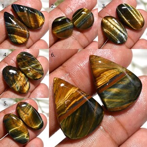 May include: A collection of polished tiger eye gemstones in various shapes. The stones display a mix of golden brown, blue, and black colors, with a chatoyant effect. The gemstones are shown in pairs, with different cuts and sizes.