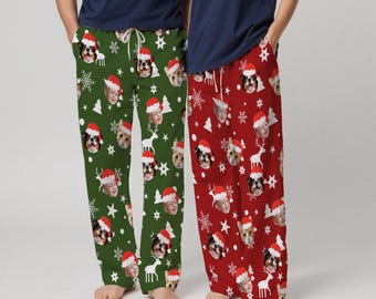 Könnte beinhalten: Grüne und rote Weihnachtspyjamahosen mit individuellem Gesichtersdruck. Die grüne Hose hat ein Muster aus Gesichtern mit Weihnachtsmützen, Schneeflocken, Sternen und Rentieren. Die rote Hose hat ein ähnliches Design. Beide haben einen Kordelzug in der Taille.