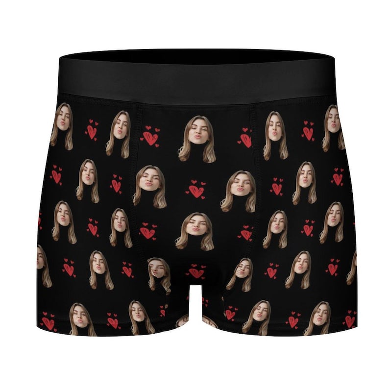May include: Black boxer briefs with a repeating pattern of a woman's face and red hearts. The woman is wearing a black turtleneck and making a kissing face. The waistband is solid black.