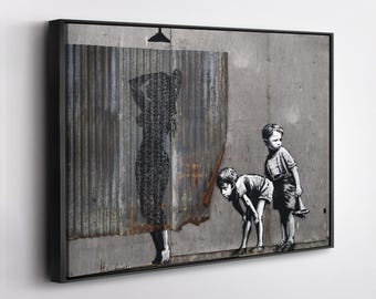 May include: Framed artwork featuring a black and white stencil of a person showering behind a corrugated metal sheet. Two children are depicted observing the scene. The artwork is mounted in a black frame.