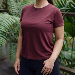 May include: A solid maroon short-sleeved t-shirt with a crew neckline. The shirt features a plain, unpatterned design with a standard fit, short sleeves, and a straight hemline, providing a simple and functional garment for everyday wear.