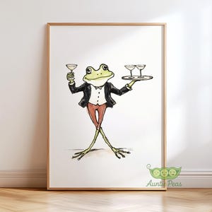 May include: Watercolor illustration of a frog waiter in a tuxedo holding a martini glass and a tray with two glasses. The frog is green with red pants and a white shirt. The artwork is in a wooden frame.