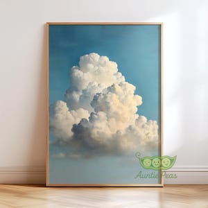 May include: A framed print depicting a large, white cloud formation against a pale blue sky. The cloud has a textured appearance and soft edges. The frame is made of light-coloured wood. The image evokes a sense of calm and is a landscape.