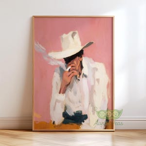 May include: A framed art print featuring a person in a white cowboy hat and shirt, smoking a cigarette. The artwork has a pink background and a wooden frame. The style is painterly with visible brushstrokes.