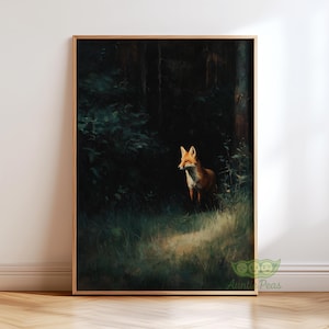 Op de afbeelding: Een ingelijste kunstdruk met een vos in een bos. De vos heeft rood-oranje vacht en staat in een zonneplek. De achtergrond is een donker bos met groen gebladerte en hoge bomen. De lijst is lichtbruin.