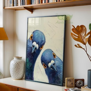 May include: Framed art print featuring two blue pigeons with orange eyes and white markings. The artwork has a textured, painterly style and is set against a light background. The frame is black.