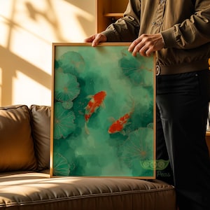 May include: A framed art print featuring two orange and white koi fish swimming in a green pond with lily pads. The artwork has a watercolor style with gold accents and is displayed in a natural wood frame.