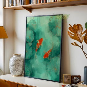 May include: Framed art print featuring two orange and white koi fish swimming in a teal pond with lily pads. The artwork has a watercolor style with gold accents and is displayed in a black frame.