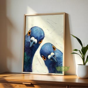 May include: A framed art print featuring a close-up of two blue pigeons with orange eyes. The artwork has a textured, painterly style, set against a white and off-white background. The frame is a light wood color.