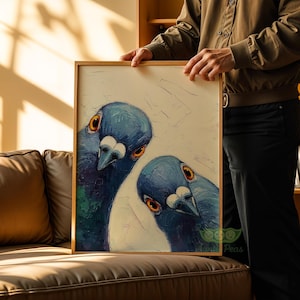 May include: A framed art print featuring a close-up of two blue pigeons with orange eyes. The artwork has a textured, painterly style, with visible brushstrokes. The frame is a light wood color, and the background is a soft white.