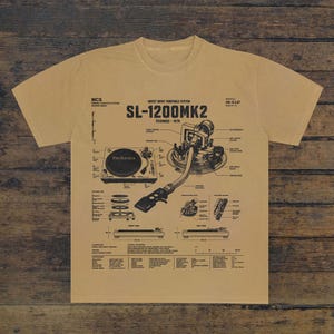 Könnte beinhalten: Ein beiges T-Shirt mit einer schwarzen technischen Zeichnung eines Technics SL-1200MK2 Plattenspielers mit Direktantrieb. Die Grafik enthält detaillierte Schaltpläne, Beschriftungen und Spezifikationen für die Komponenten des Plattenspielers.